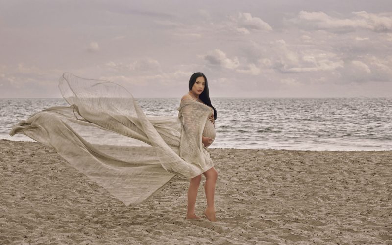 beach maternity photography Southern California flowing fabric dress pregnant woman standing ocean